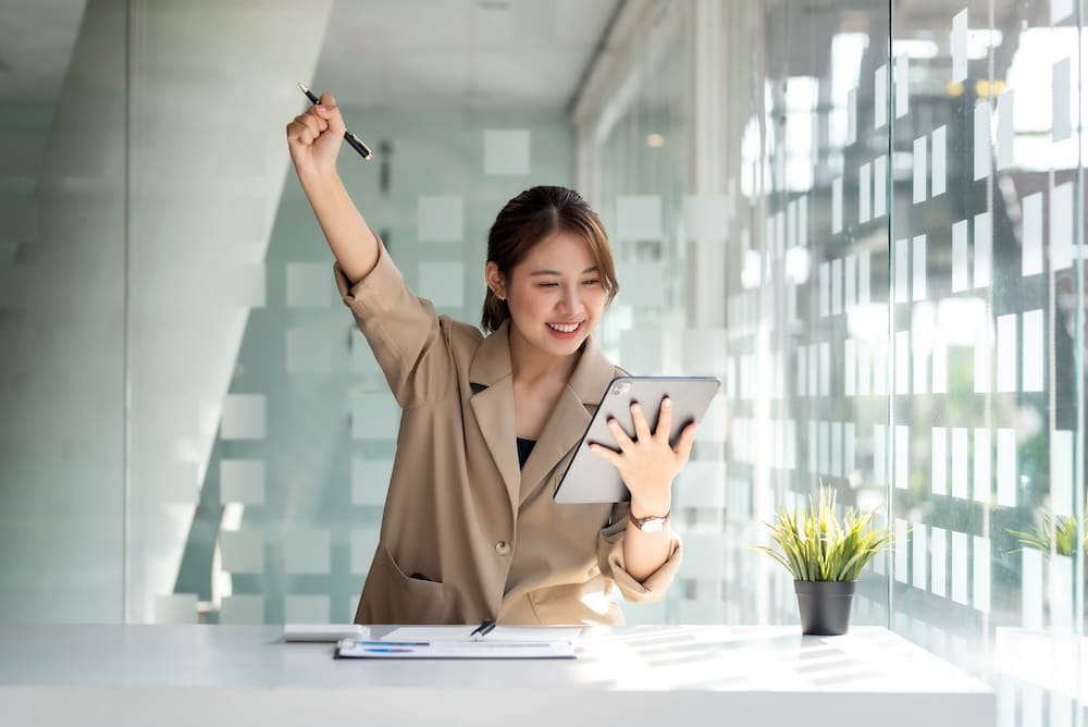 タブレットを見て手を上げて喜ぶ女性