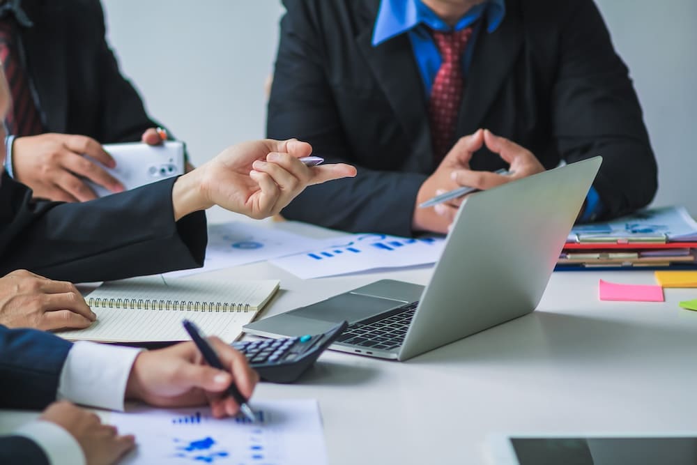 データの書類とパソコンで打ち合わせをする会社員