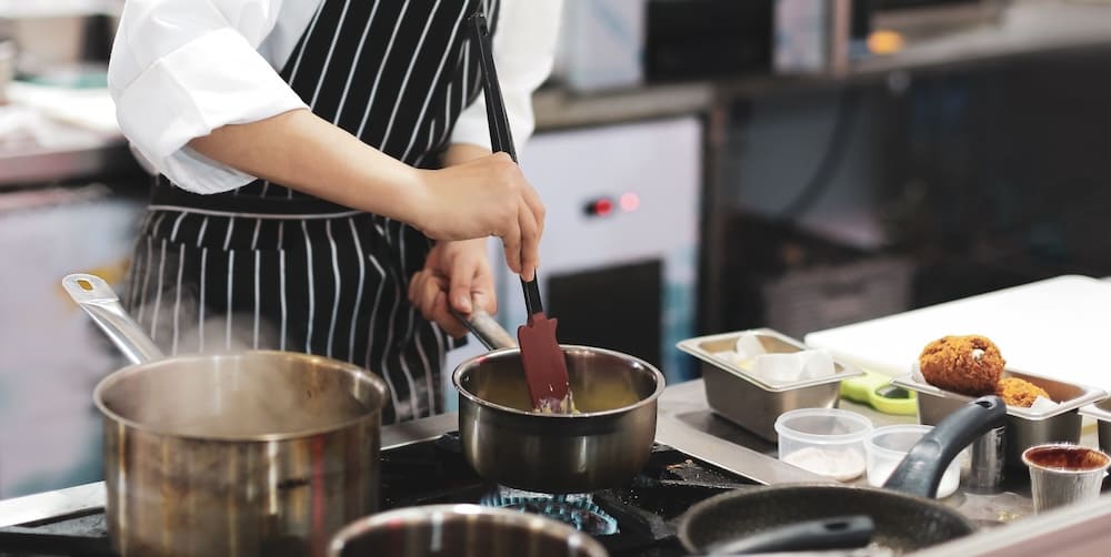 厨房の鍋で調理をするシェフ