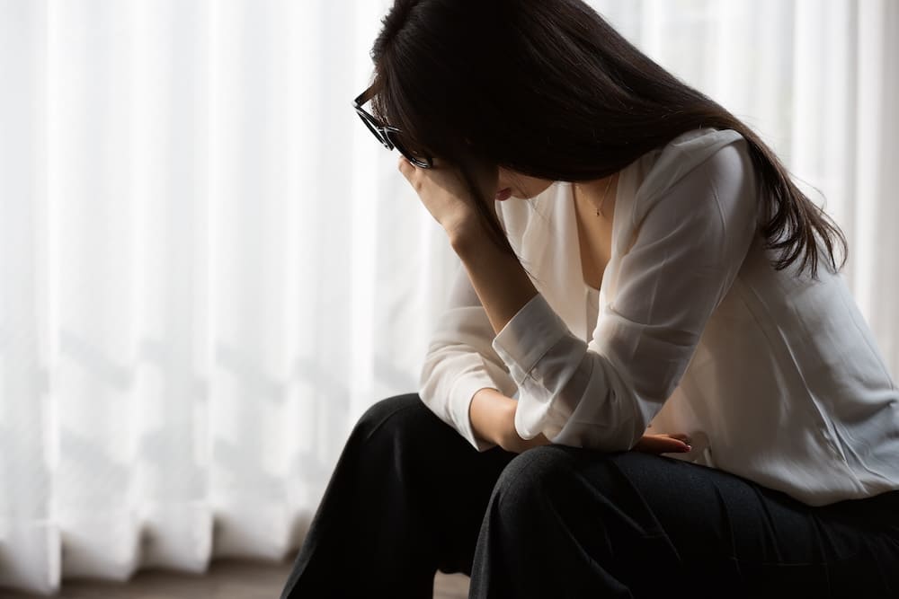 しゃがみ込んで頭を抱えている女性