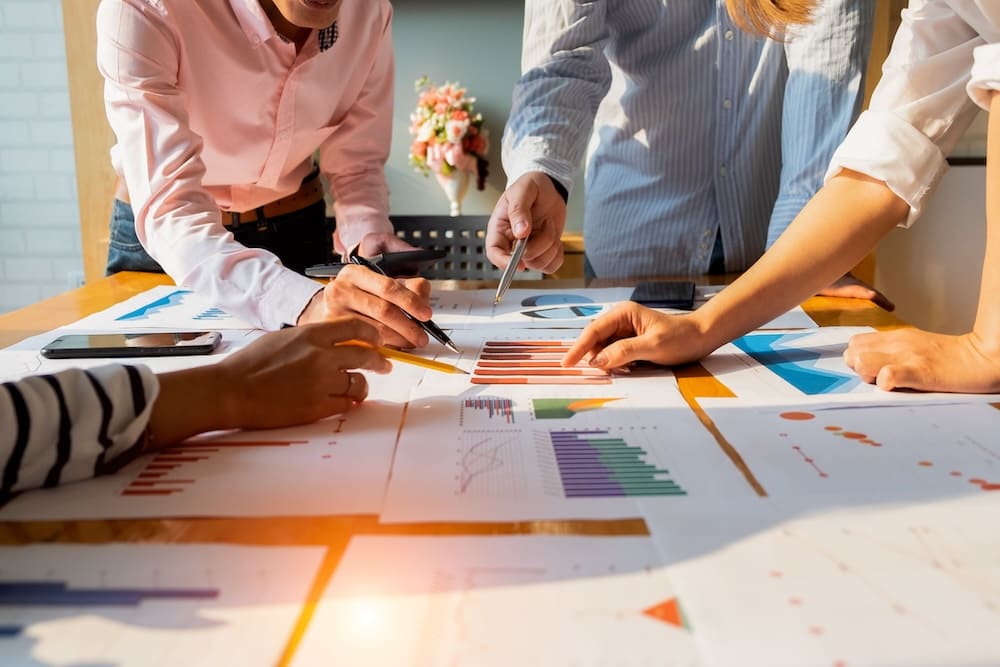 書類を見ながら打ち合わせをする複数の男女