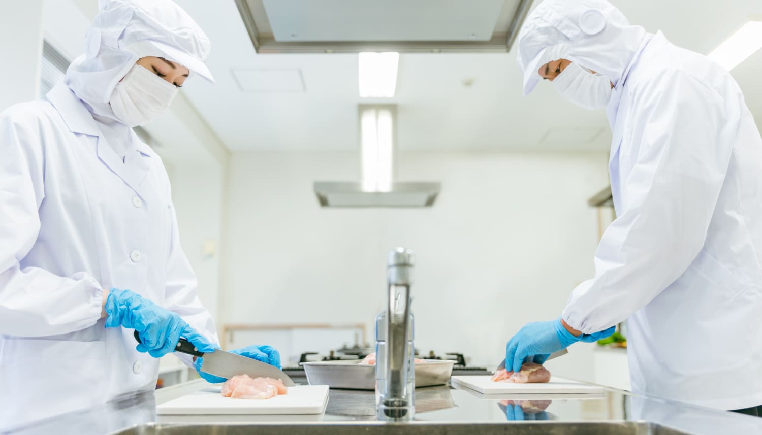 食品をカットする白衣を着た衛生士