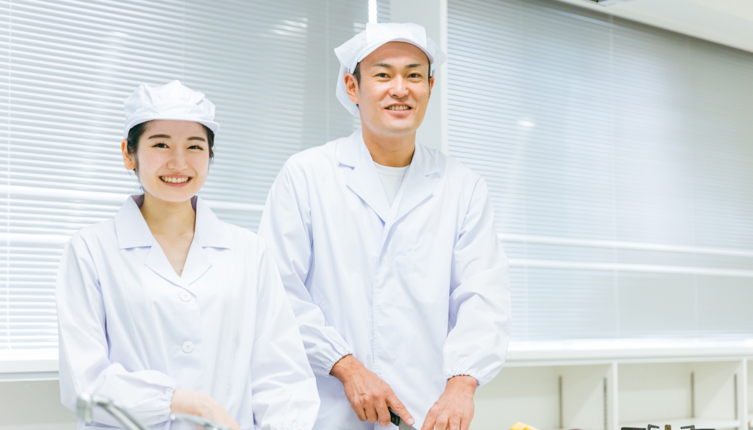 野菜をカットする白衣を着た女性と男性の調理師