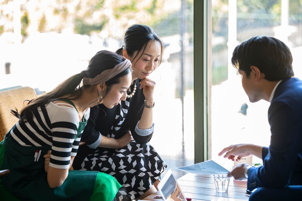 営業マンと女性2人が打ち合わせを書類を見ながら打ち合わせ