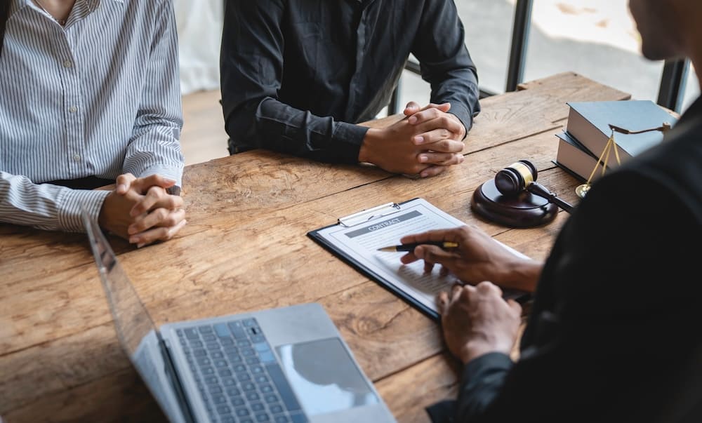 テーブルで書類を見ながら打ち合わせをする男性2人と女性