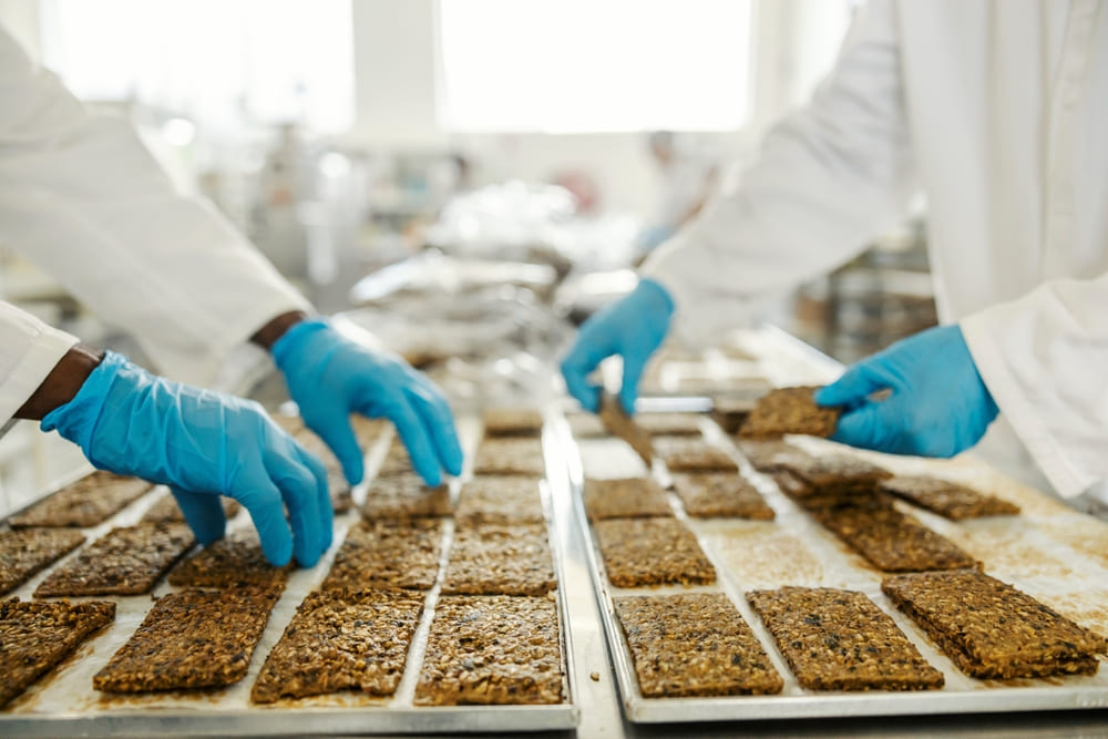 ビスケットを検査する白衣を着た手袋をつけた作業員