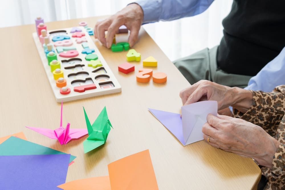 折り紙でおられたツルと折り紙を折るお年寄り