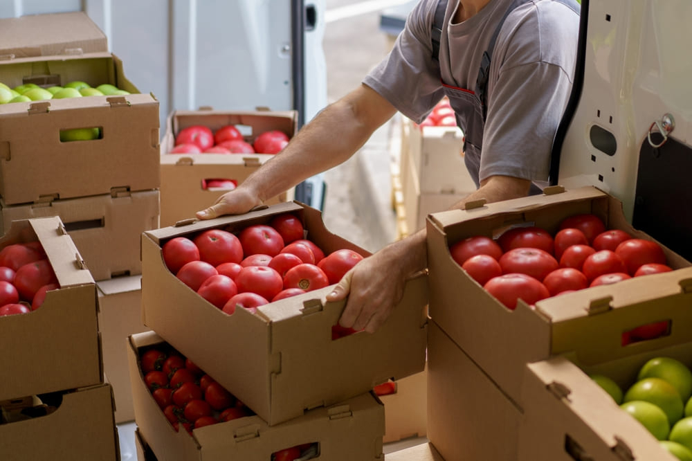 トラックからトマトなど野菜を運ぶ男性の手元