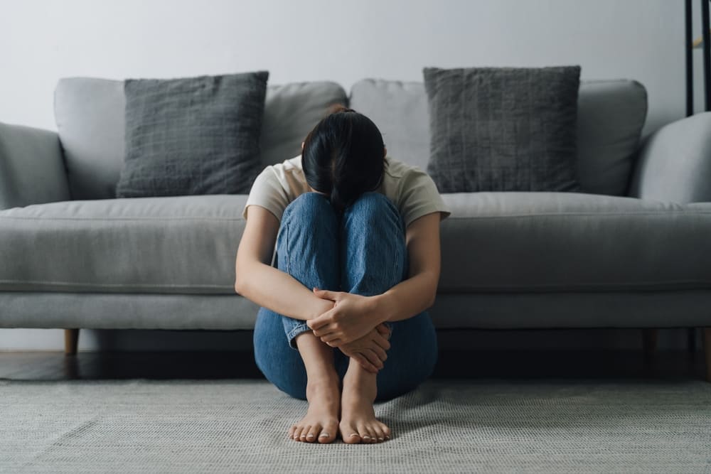 腕を抱えてうずくまる女性