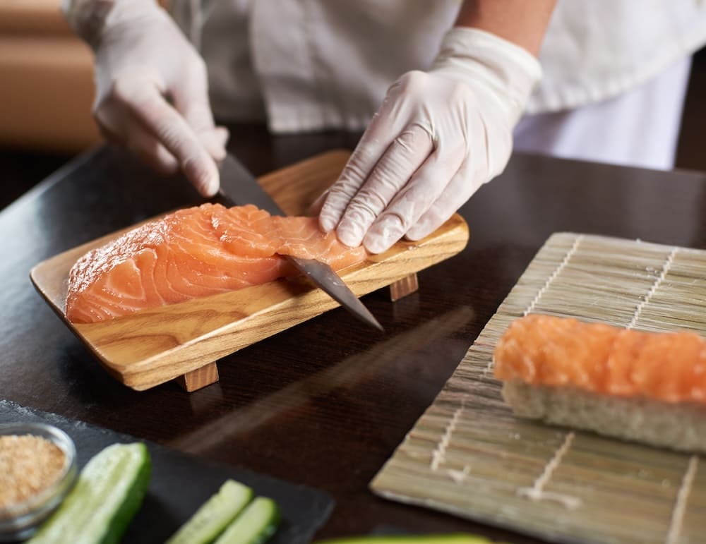 サーモンを包丁でカットする寿司職人