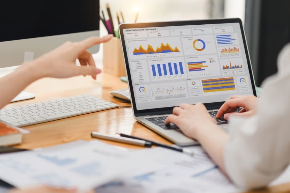 2人のビジネスマンまたは会計士チームが、ノートパソコンの画面でデータチャート、グラフ、ダッシュボードを分析して、統計レポートを作成し、オフィスの財務データについて議論しています