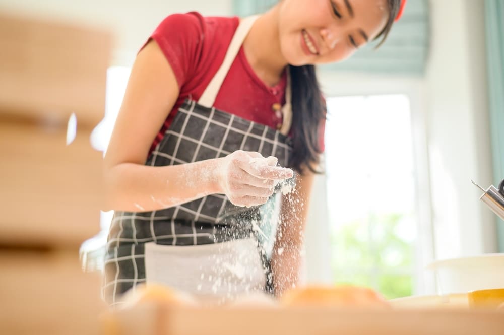 若い美しい女性がベーカリーで焼いている 