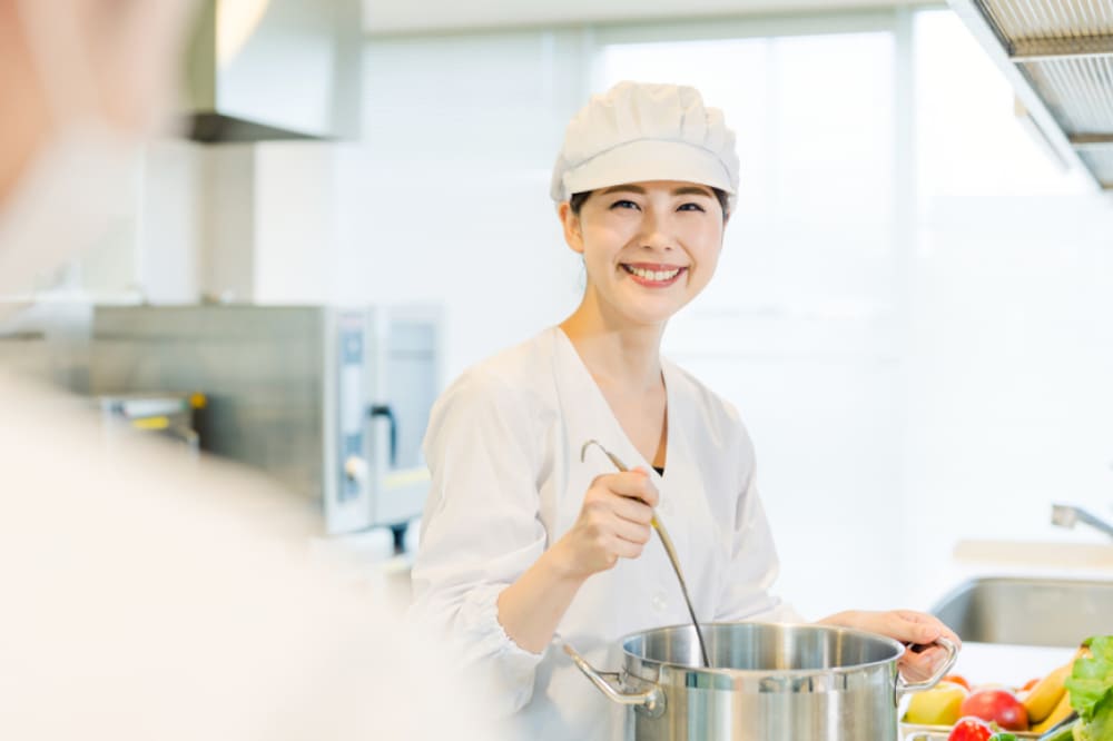 キッチンで笑顔で調理する日本人女性
