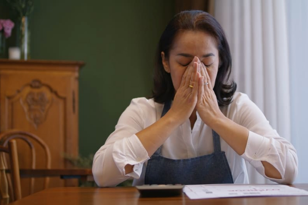 小さな店で口をおおって落ち込み悲しそうにする女性