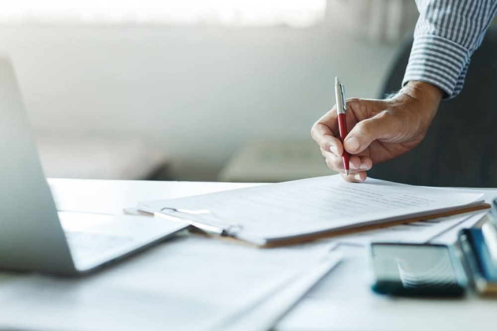 ジネスマンがコンピュータの前で文書レポートを作成している手元