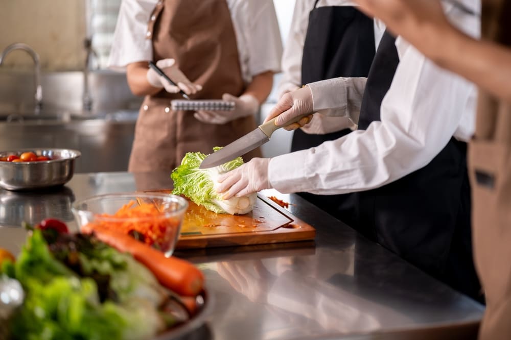 白菜を切る女性とメモをもって説明する女性の手元